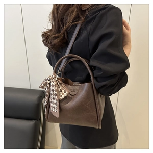 Detail of vintage brown tote bag with leather texture and silk scarf decoration