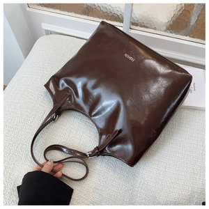 Detail of glossy deep brown tote bag featuring white FASHION lettering and silver hardware