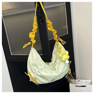 Detail of light green nylon hobo bag with yellow pleated strap and floral pendant