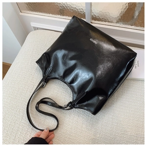 Detail of glossy black faux leather tote with FASHION text for daily commute
