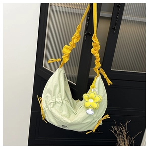 Close-up of light green nylon crescent bag featuring yellow ruffled drawstring straps