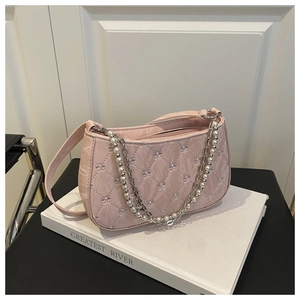 Détail du sac matelassé rose avec nœuds et chaîne perlée posé sur des livres