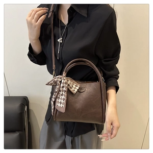 Detail of brown litchi leather bucket bag with silk scarf and gold ring handles