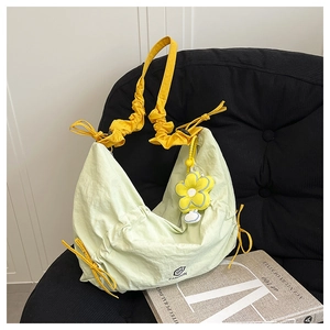 Detail of nylon crescent bag featuring a yellow floral charm and QS FASHION logo