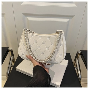 Détail du sac sous l'aisselle blanc matelassé avec élégante chaîne en perles et métal