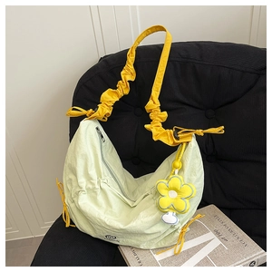 Detail of light green pleated nylon crescent bag with yellow ruched strap and flower charm