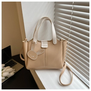 Close-up of khaki bucket bag with cute rabbit charm and detachable shoulder strap
