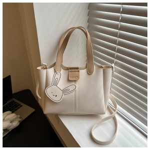 Detail of beige bucket bag with leather texture and cute fashion rabbit charm