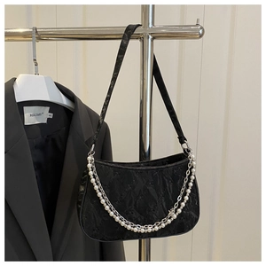 Detail of black quilted shoulder bag with silver and pearl chain on a metal hanger