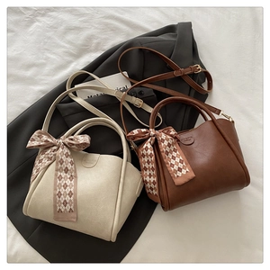 Detail of premium bucket bag showing texture, decorative scarf, and embossed logo
