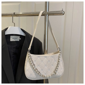 Detail view of quilted cream shoulder bag featuring pearl and silver chain straps