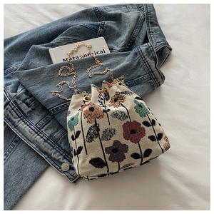 Vue détaillée du sac seau tissé à motif floral avec chaîne en métal dorée chic