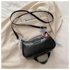 Détail du sac sous l'aisselle en similicuir noir avec rubans sur un blazer beige