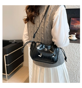 Detail of black embossed leather crossbody bag with silver butterfly charms and drawstring
