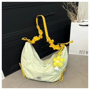Detail of light green nylon crescent bag with contrasting yellow pleated strap and floral charm