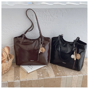 Detail of high-gloss leather tote bags with FASHION logo and sports theme pendants