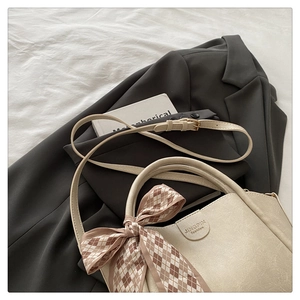 Detail of cream leather handbag with silk scarf bow and jingpin embossed logo