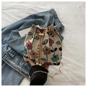 Détail d'un sac seau floral en tapisserie avec chaîne dorée et détails de perles