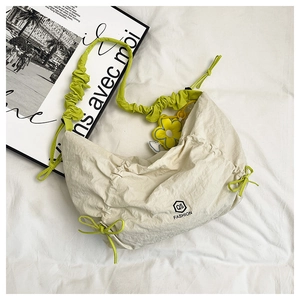 Detail of cream nylon crescent bag featuring green drawstring strap and sunflower charm