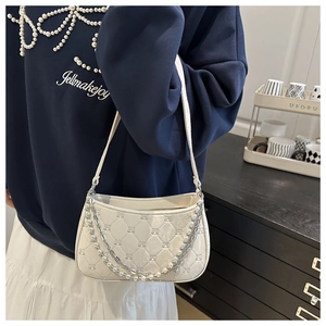 Detailed shot of quilted ivory shoulder bag with elegant pearl and metal double chains