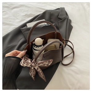 Detail view of coffee brown bucket bag with silk scarf and daily essentials inside