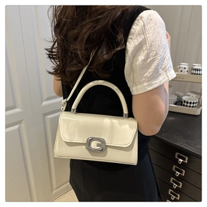 Détail d'un sac à main crème avec boucle en strass G et fine bandoulière amovible