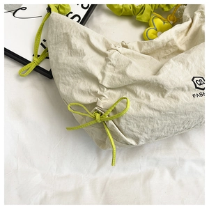 Detail of cream canvas bag with green drawstring bow and floral charm accessory