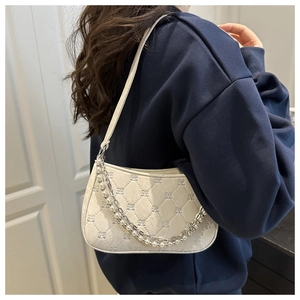 Detail of cream quilted handbag featuring pearl accent chain and elegant diamond pattern