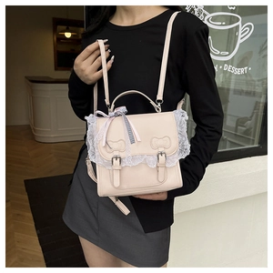 Detail of cream pink crossbody bag featuring white lace trim and bow relief decor