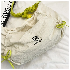 Detail of off-white nylon crescent bag with lime green drawstring and logo