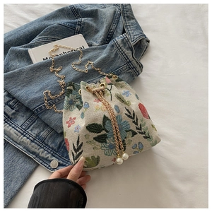 Détail du sac seau en tapisserie florale avec chaîne dorée et détails de perles blanches