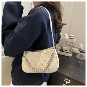 Détail du sac à bandoulière crème avec texture matelassée et chaîne en perles élégante
