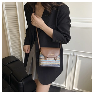 Detail of colorful rainbow woven straw crossbody bag with brown leather flap closure