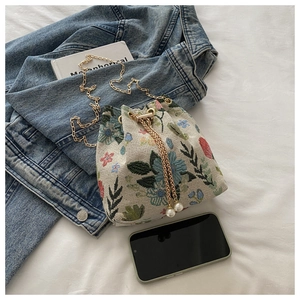Vue détaillée du sac seau en jacquard floral avec cordon perlé et bandoulière dorée