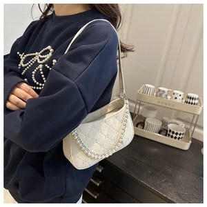 Gros plan sur le sac matelassé blanc orné d'une double chaîne de perles élégante