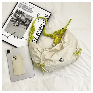 Detail of cream nylon hobo bag with neon green ruffled strap and sunflower charm decor