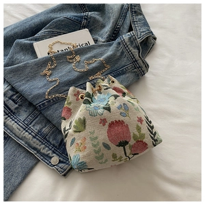 Détail du tissu jacquard floral sur sac seau avec chaîne dorée et cordon de serrage