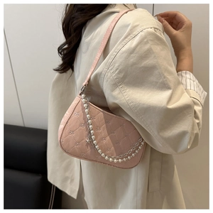 Détail du sac baguette matelassé rose clair avec chaîne en perles et breloques étoiles