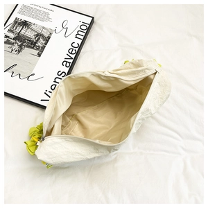 Detailed interior of a cream shoulder bag with lime green ruched handle on bedding