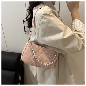 Détail du sac sous le bras rose matelassé avec texture nœud et chaîne de perles