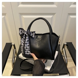 Detail of black faux leather bucket bag with gingham bow and round top handle