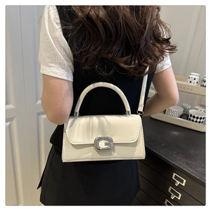 Detailansicht der cremefarbenen PU-Lederhandtasche mit funkelnder G-Schnalle mit Diamanten