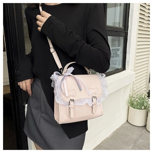 Detail of pink PU leather crossbody bag with white lace edges and ribbon bow accent