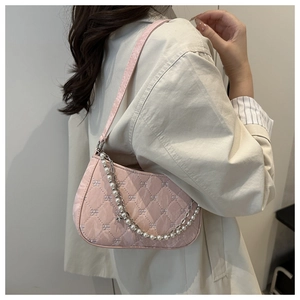 Détail d'un sac bandoulière rose matelassé avec chaîne perle et motif nœud