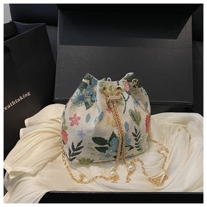 Détail du sac seau rétro à fleurs avec breloques perles et bandoulière en chaîne dorée