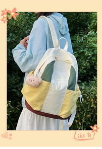 Outdoor shot of a multi-color nylon backpack with a plush bear charm and adjustable straps