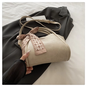 Detail of beige faux leather tote bag with brown checkered scarf and long strap