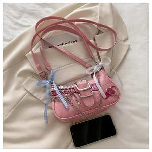 Sac sous l'aisselle rose avec chaînes en métal, étoiles et nœuds sur fond de blazer