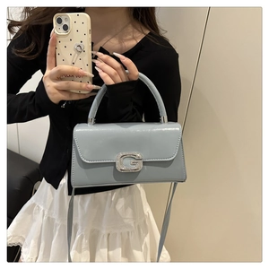 Detail of light blue glossy leather handbag with large sparkling crystal G-buckle