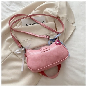 Detailed view of pink shoulder bag with decorative plaid ribbons on beige blazer